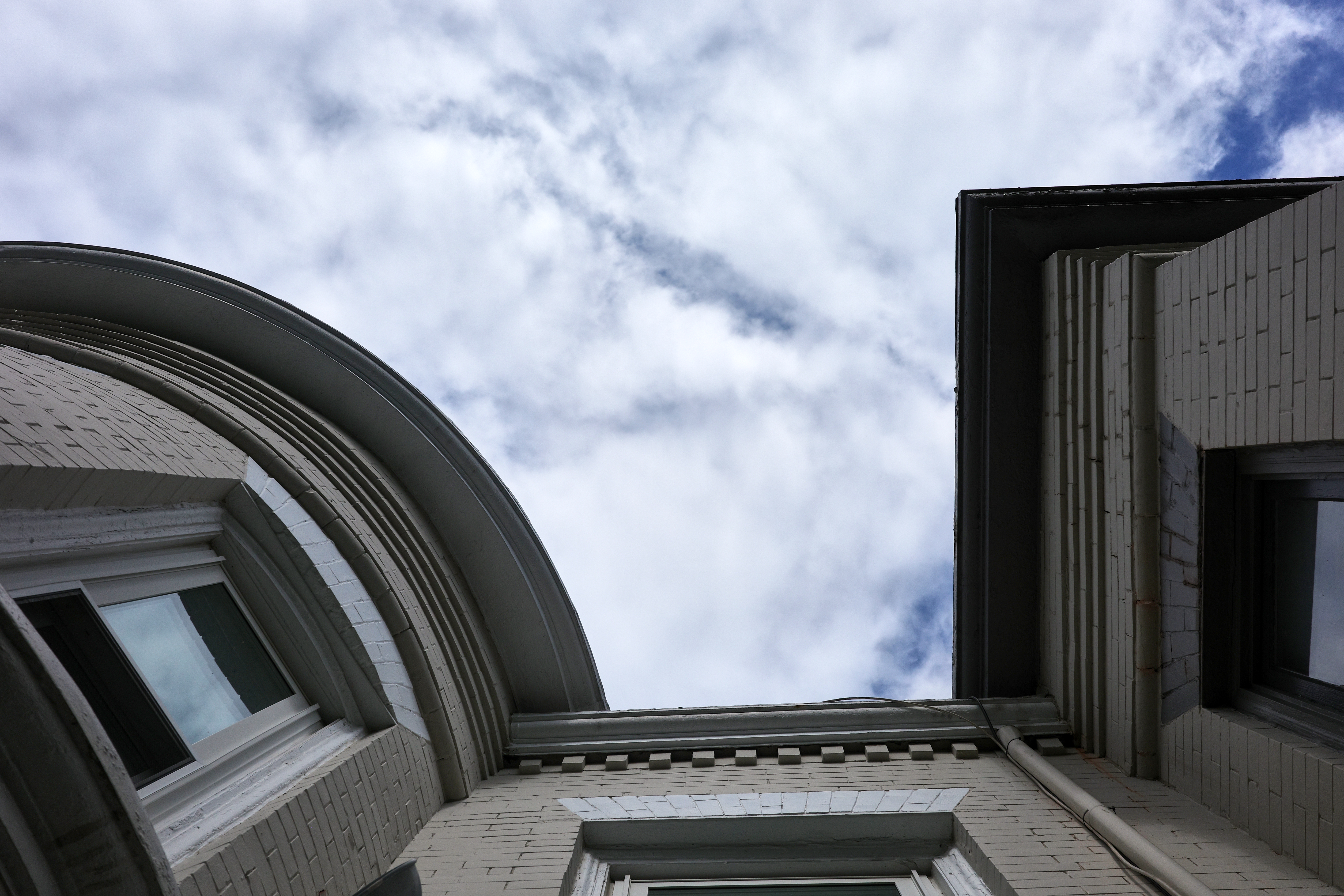 A rowhouse cornice against a marbled sky