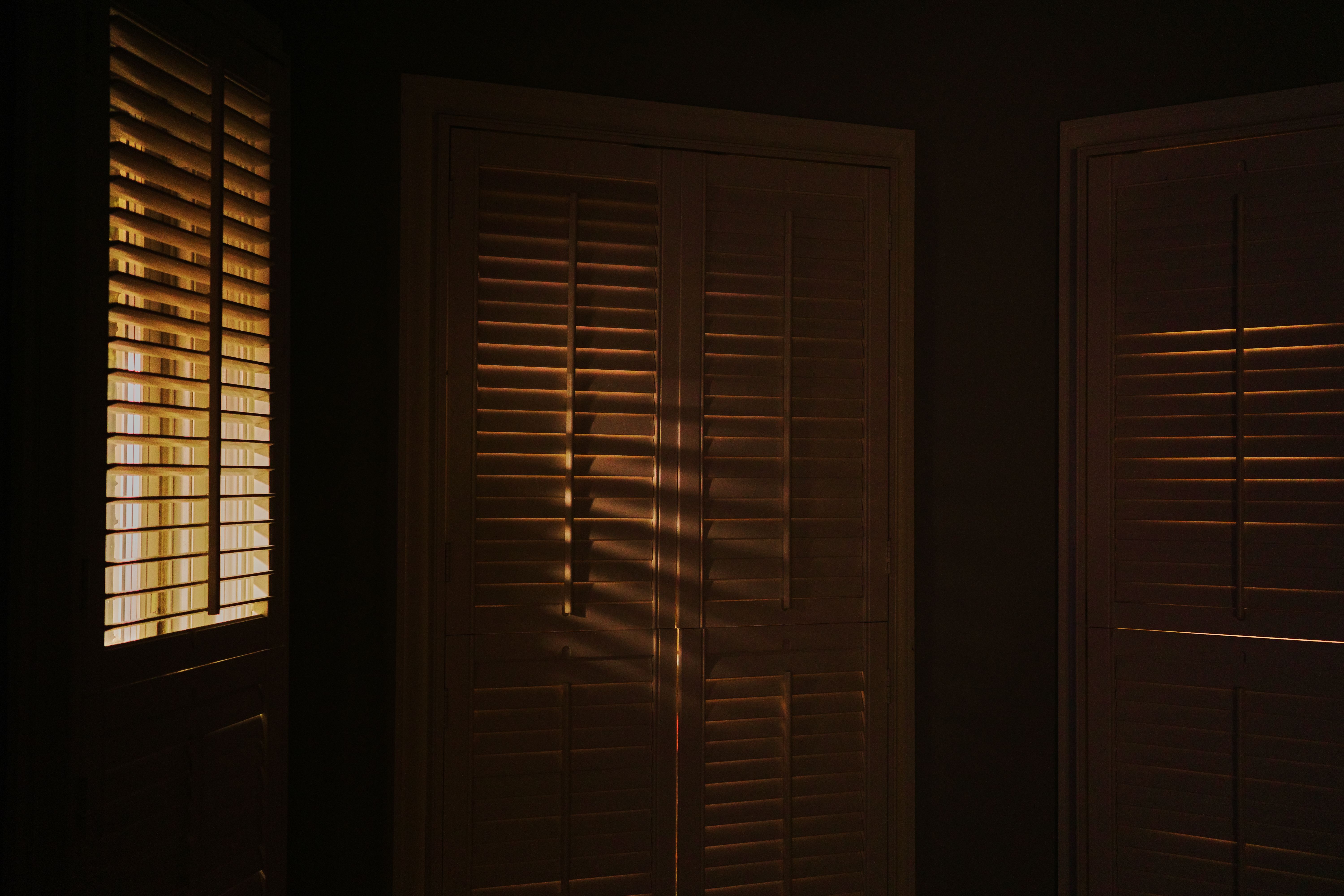 A dim interior with shutters glowing amber at dusk